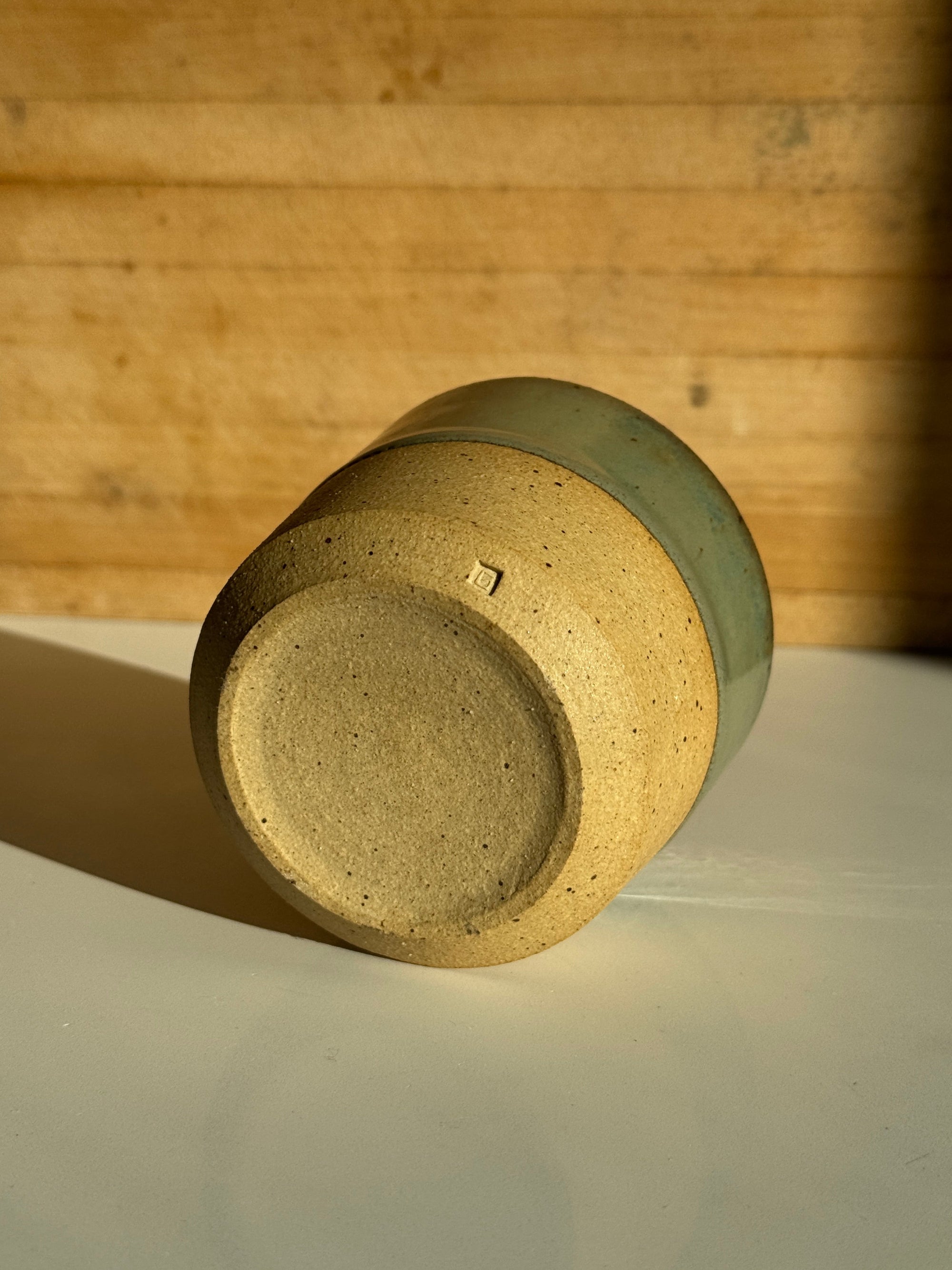 Ceramic cup with green glaze on light tan clay body