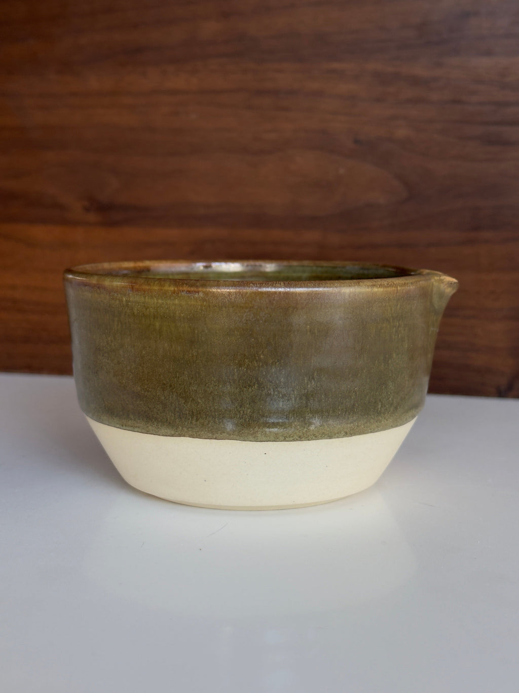 Ceramic bowl with green glaze on a wooden surface