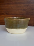 Ceramic bowl with green glaze on a wooden surface
