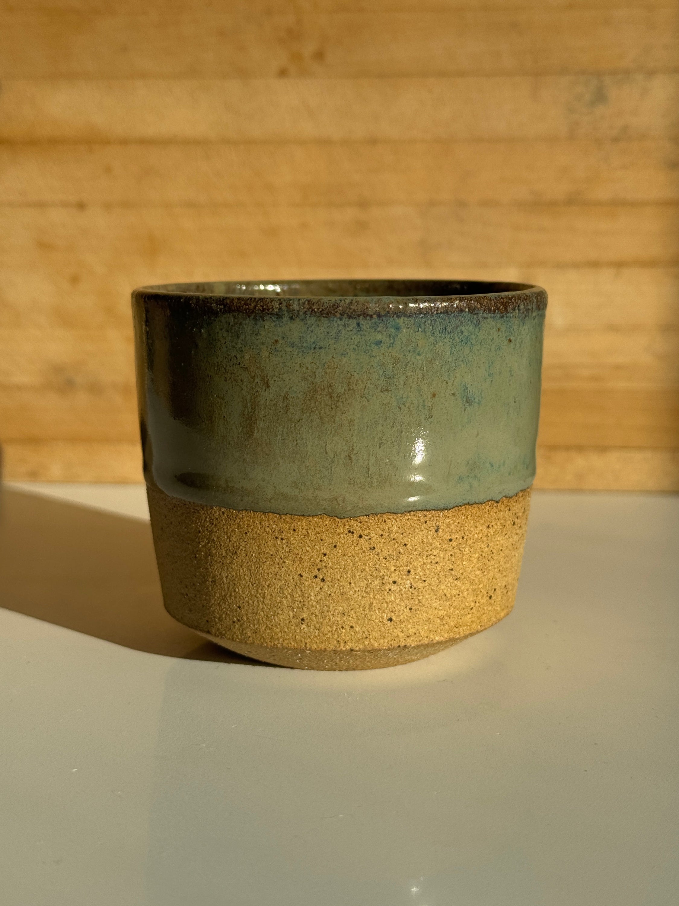 ceramic mug with green denim glaze over light clay.